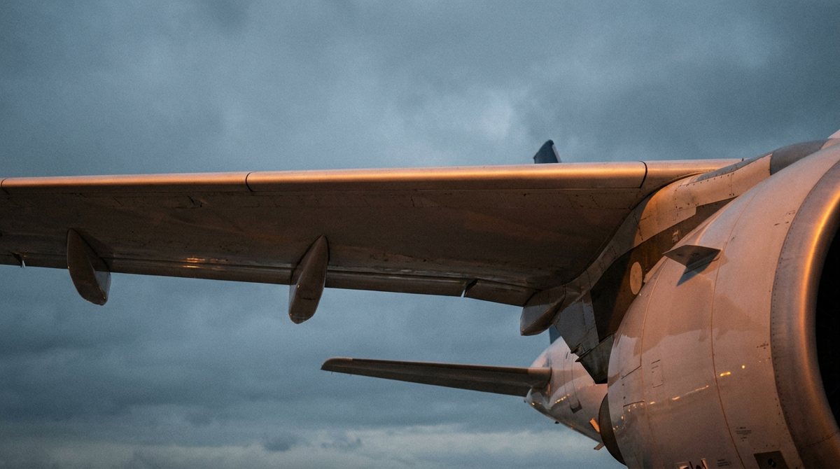Modern jet wing and engine pylon from below at dawn